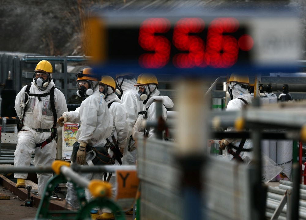 Workers in protective suits carry out decommissioning near Fukushima Daiichi’s No. 2 and No. 3 reactors, as a monitoring post records 55.6 microsieverts per hour, ahead of the 15th anniversary of Japan’s 2011 tsunami and nuclear disaster. — Reuters pic