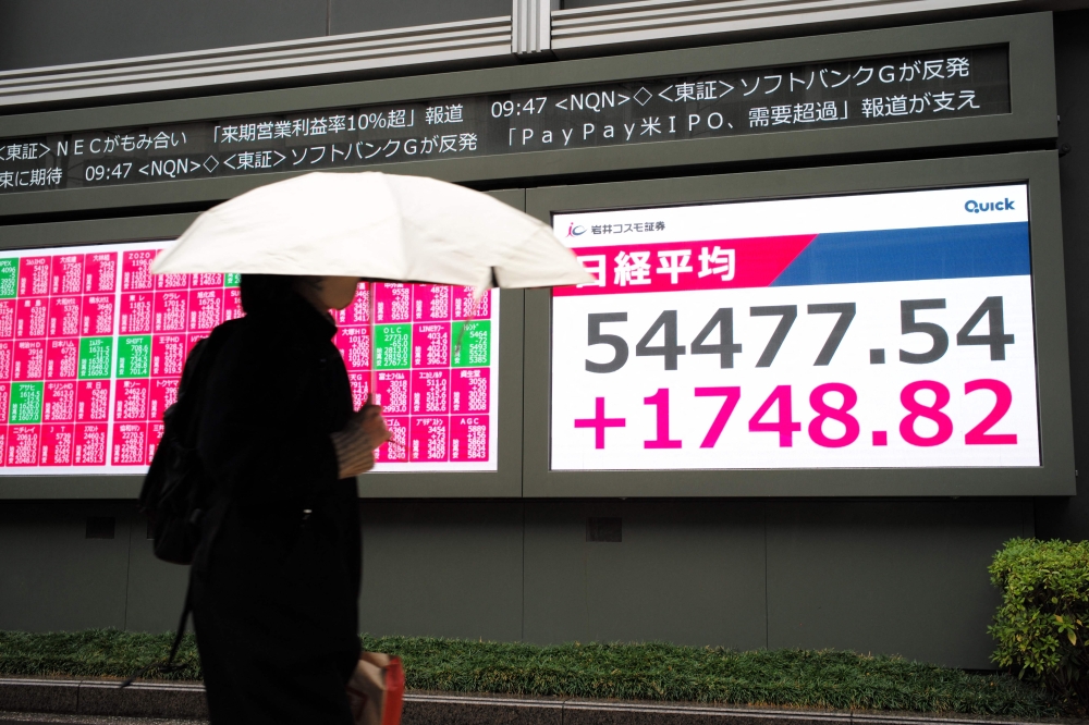 A woman walks in front of an electronic quotation board displaying the Nikkei Stock Average on the Tokyo Stock Exchange along a street in Tokyo on March 10. — AFP pic