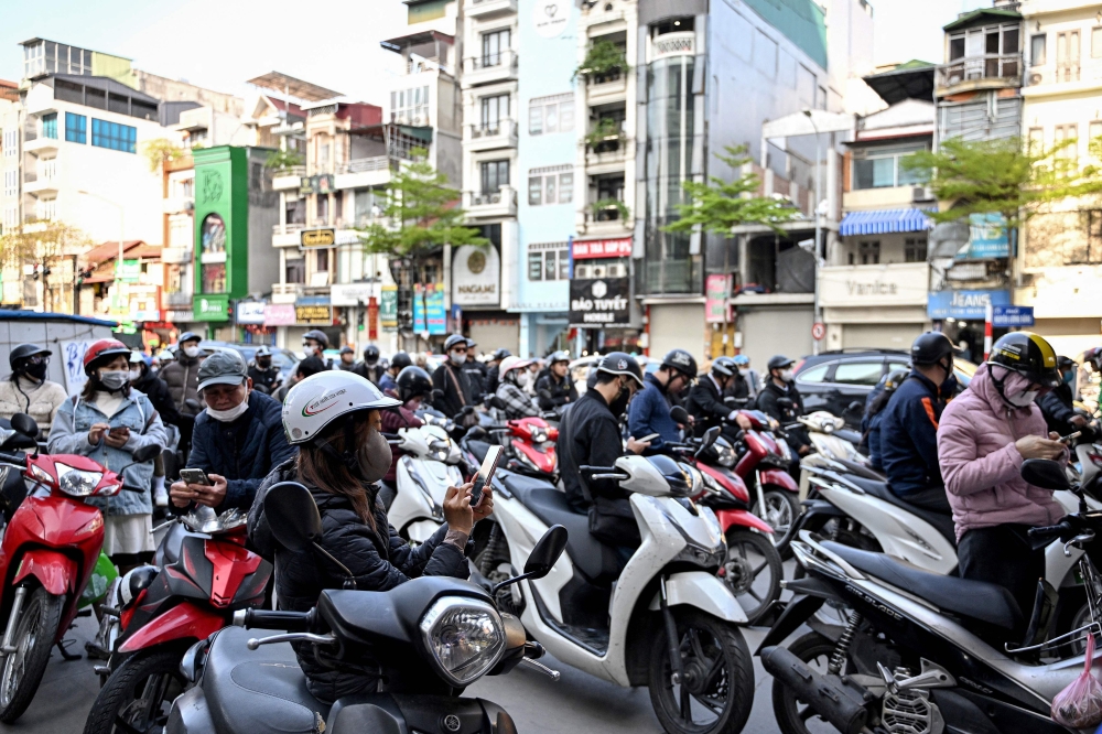 Motorists queue to pump gasoline into their vehicles at a gas station in Hanoi on March 10, 2026. — AFP pic