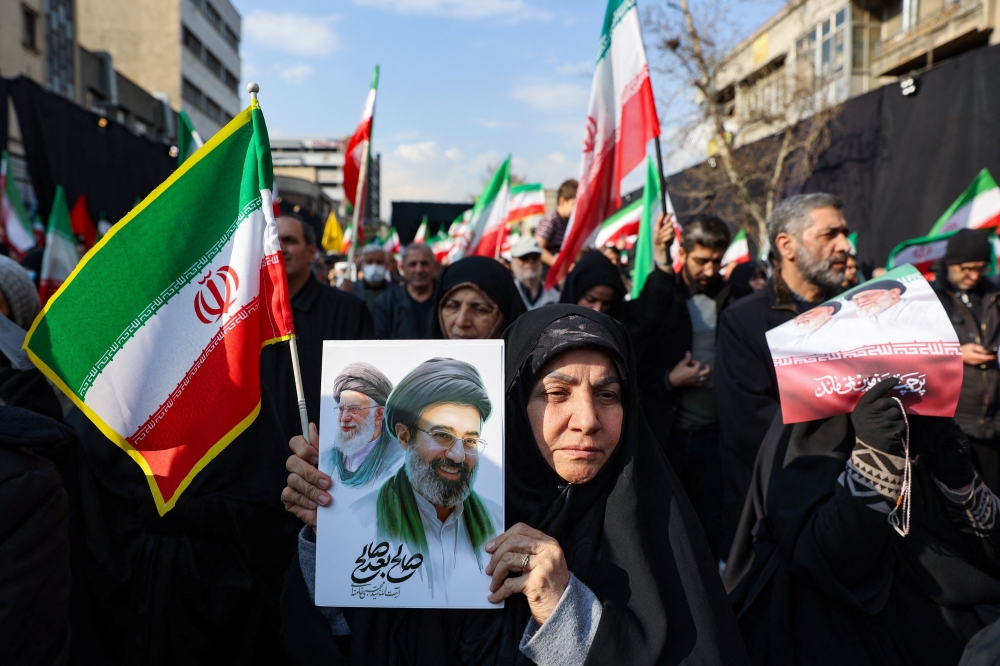 A woman holds a placard with an image of Iran’s new supreme leader Mojtaba Khamenei alongside late Iranian Supreme Leader Ayatollah Ali Khamenei, on the day of a gathering to support Mojtaba Khamenei, amid the US-Israeli conflict with Iran, in Tehran March 9, 2026. — Reuters pic