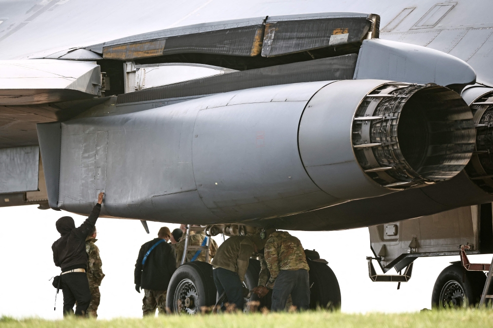 Members of the US Air Force (USAF) work on a USAF B-1 Lancer bomber parked on the tarmac at RAF Fairford in south-west England on March 10. — AFP pic