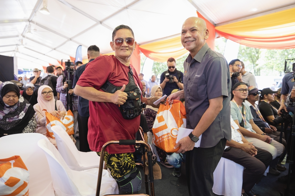 Domestic Trade and Cost of Living Minister Datuk Armizan Mohd Ali (right) presents a contribution to Shaari Mohd Yusof (front, left) during the announcement of the Hari Raya Aidilfitri Maximum Price Scheme and Madani Rahmah Sales programme at Tasek Tambahan Recreational Park, Ampang, yesterday. — Bernama pic
