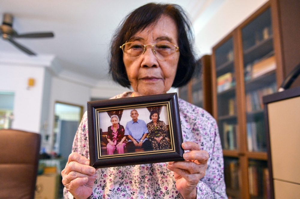 The sister of national journalism figure Adibah Amin, Khalilah Fadzilah Amin, shows a photo of the siblings while being interviewed about her sister’s health, which is now reported to be stable despite her continued weakness and need for full-time care. — Bernama pic 