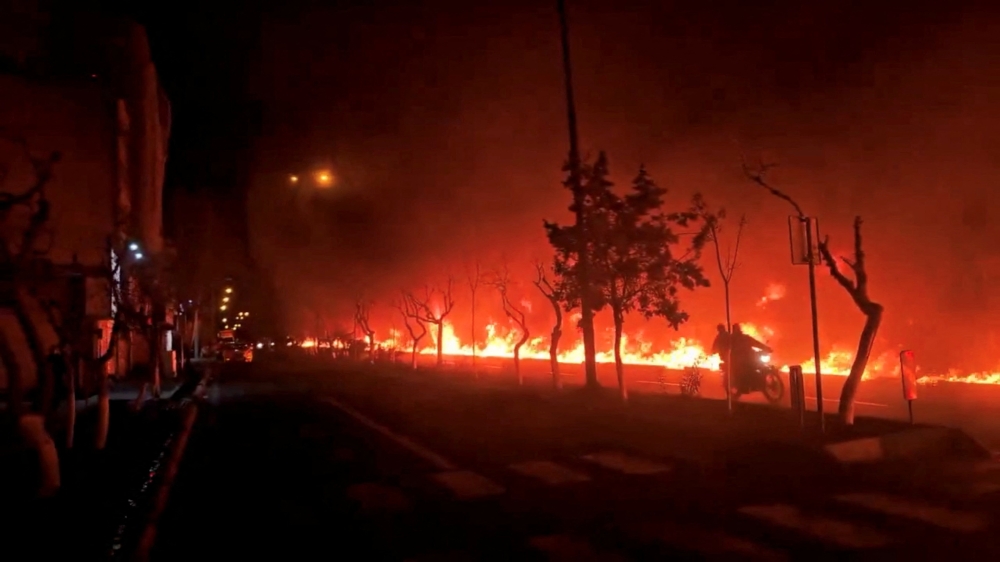 A motorcycle passes by fire burning along Tehran’s Koohsar Boulevard, Iran, in this screengrab from video obtained from social media and released on March 8, 2026, amid the US-Israeli conflict with Iran. Iranian media reported it was oil burning after it spilt into Tehran's sewage system following airstrikes on the Shahran oil depot. — Social media pic via Reuters