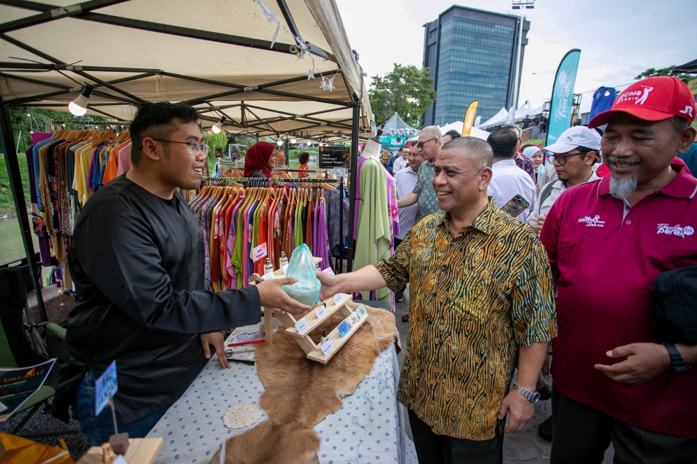 Perak Menteri Besar Datuk Seri Saarani Mohamad (second left) hands out bubur lambuk to traders during the Ipoh Raya Fiesta 2026 Riverfront @ Old Town at Kinta Riverwalk on March 14, 2026. — Bernama pic