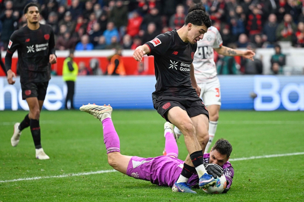 Bayer Leverkusen's Algerian midfielder #30 Ibrahim Maza and Bayern Munich's German goalkeeper #26 Sven Ulreich vie for the ball during the German first division Bundesliga football match between Bayer 04 Leverkusen and FC Bayern Munich in Leverkusen, western Germany on March 14, 2026. — AFP pic 