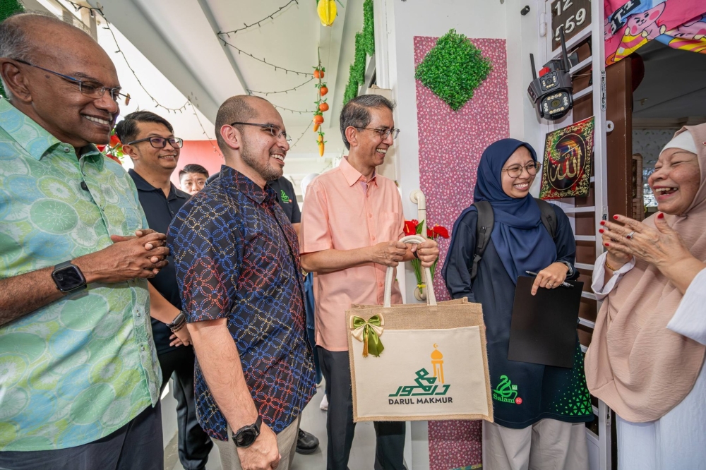 Acting Minister-in-charge of Muslim Affairs Faishal Ibrahim (centre) meeting zakat beneficiaries in Yishun on March 14. Also with him are Home Affairs Minister K. Shanmugam (left) and Nee Soon GRC MP Syed Harun Alhabsyi.— Picture via Facebook/MUIS