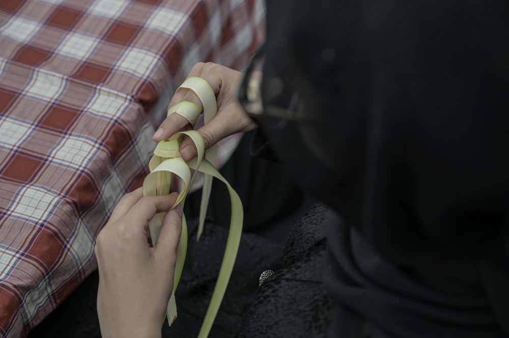 Nur Fatin Yasmin Firdaus demonstrates how to weave a ketupat casing the traditional way. — Bernama pic