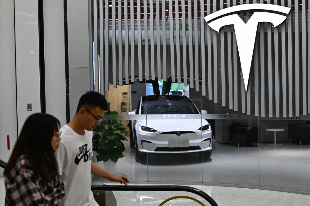 People walk past a Tesla shop at a shopping mall in Beijing on July 9, 2024. — AFP pic