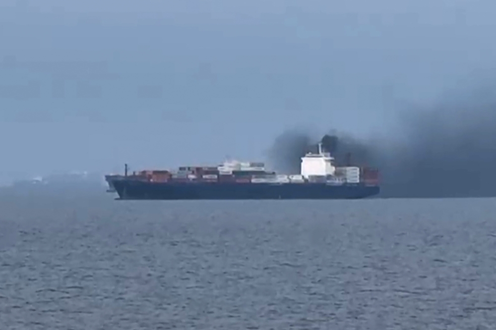 Smoke rises from the Source Blessing cargo vessel in the Gulf, north of Dubai, on March 12, 2026, as seen from a nearby ship. —  UGC video framegrab handout via AFP