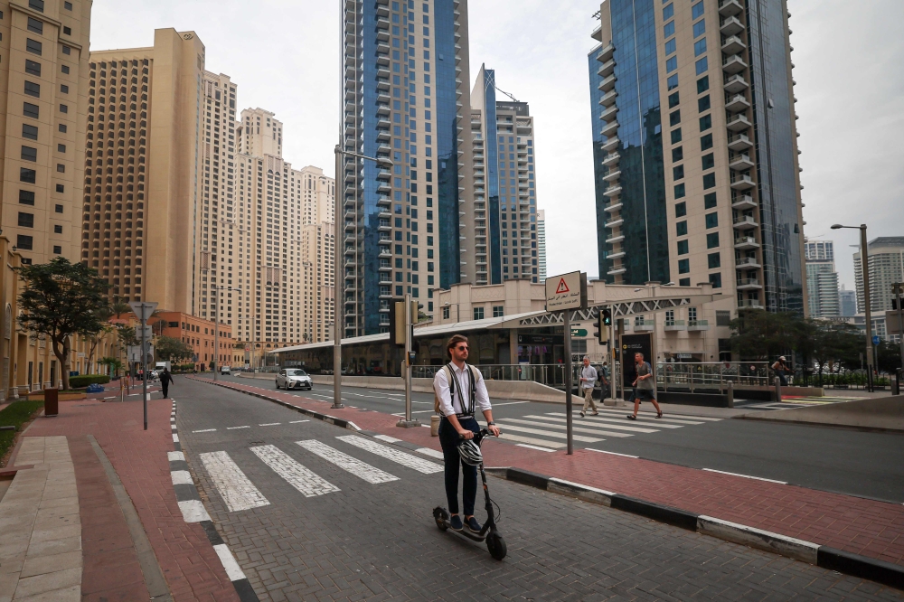 A man rides a scooter along a street with little foot traffic in Dubai’s Jumeirah Beach Residence on March 10, 2026 as the UAE doubles down on safety messaging amid regional conflict. — AFP pic