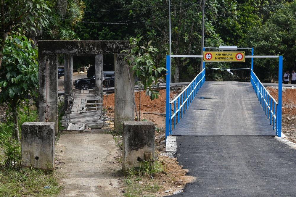 The steel bridge over Sungai Chatel Damai in Lata Rek, Kuala Krai, Kelantan (right) that officially opened on March 15, 2026 replaces the 24-year-old damaged wooden suspension bridge that collapsed on January 1. — Bernama pic