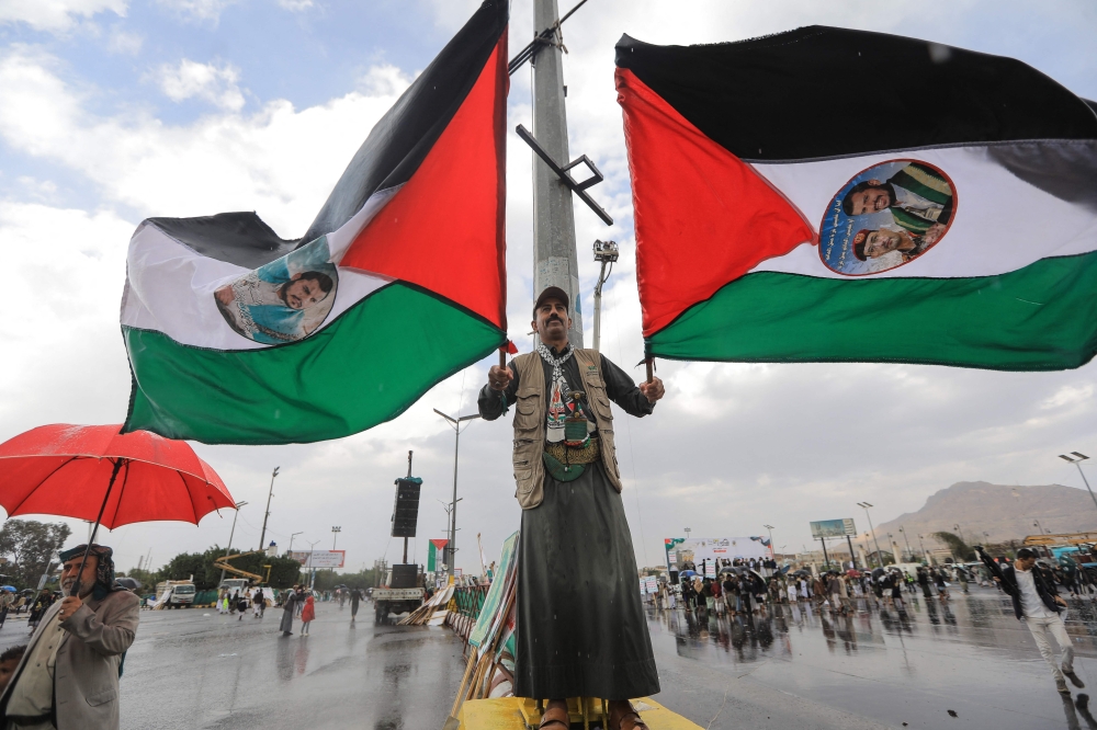 A supporter of Yemen's Huthi rebels waves Palestinian flags bearing portraits of rebel leader Abdul Malik al-Huthi during the Al-Quds (Jerusalem) Day rally, a commemoration in support of the Palestinian people on the last Friday of the Islamic holy month of Ramadan, in Sanaa on March 13, 2026. Yemen's Houthi rebels on March 9, welcomed Iran's ruling clerics appointing their slain leader's son as the country's new supreme leader, calling it a major blow for the Islamic republic's enemies as it fights a war with the United States and Israel. — AFP pic