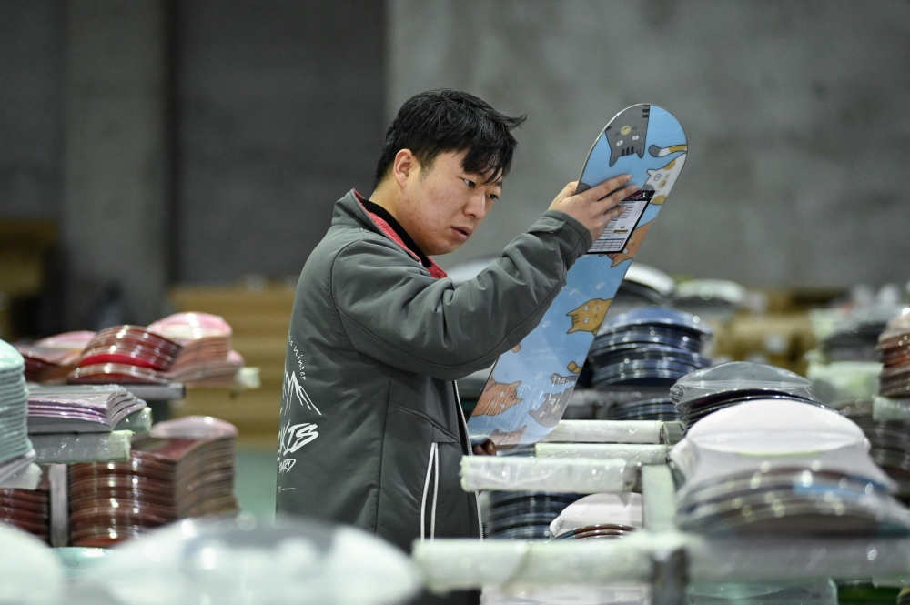 An employee checks a snowboard at Lidakis's warehouse in Zhangjiakou, in China's northern Hebei province on March 12, 2026. — AFP pic