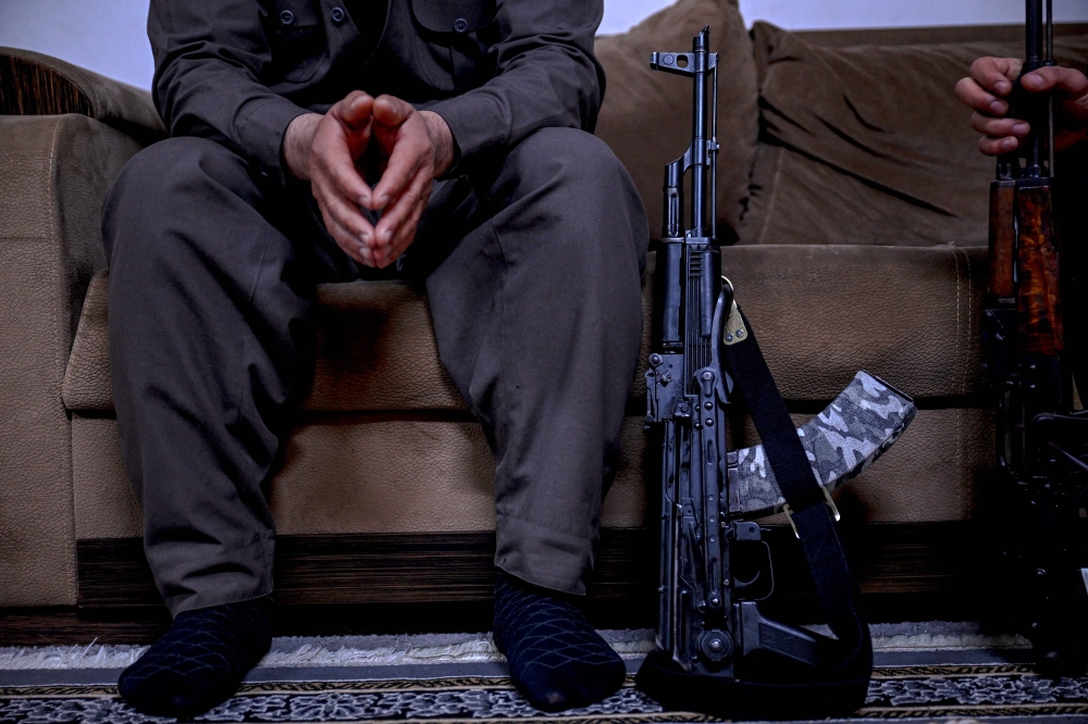 Aresto Pasbar, a Iranian who fled the country after joining the 2022 anti-government protests, sits next to a AK-47 rifle at a house in Sulaimaniyah on March 13, 2026. — AFP pic