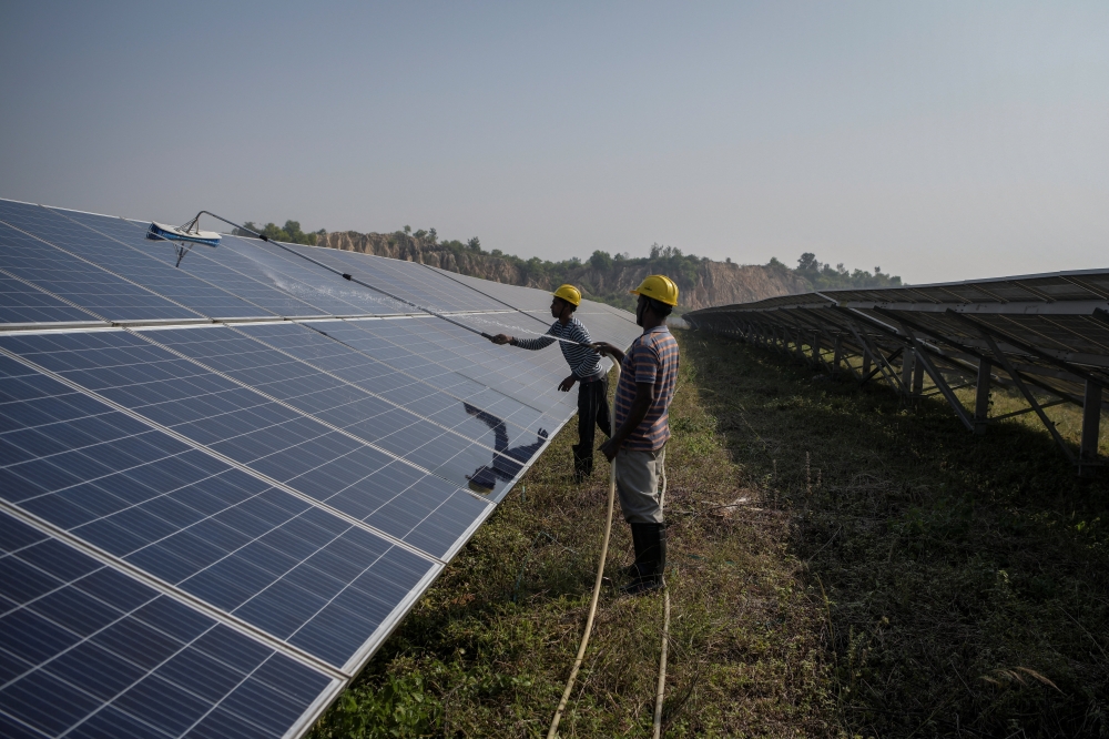 Workers clean installed solar panels at a 12MW solar PV power plant, set up as part of the land reclamation plan for the Bishrampur OC coal mining area, in Surajpur, India, November 16, 2025. — Reuters pic