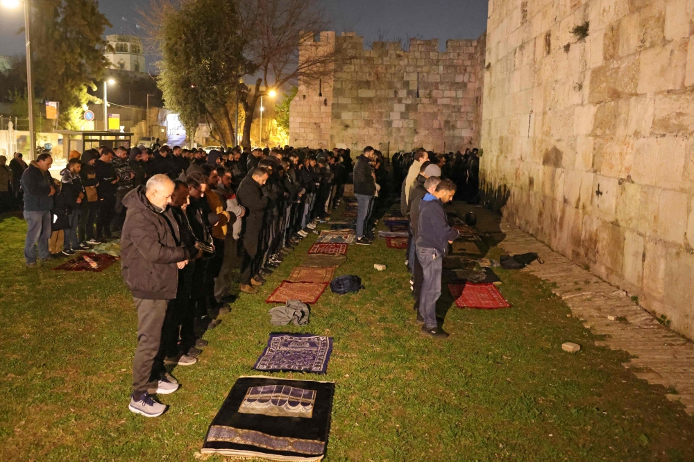 Palestinian Muslims pray outside the Old City of Jerusalem on Laylat al-Qadr or Night of Destiny, one of the holiest nights during the holy fasting month of Ramadan on March 15, 2026, as the nearby al-Aqsa Mosque remains closed following the outbreak of the US-Israel war with Iran on February 28. — AFP pic