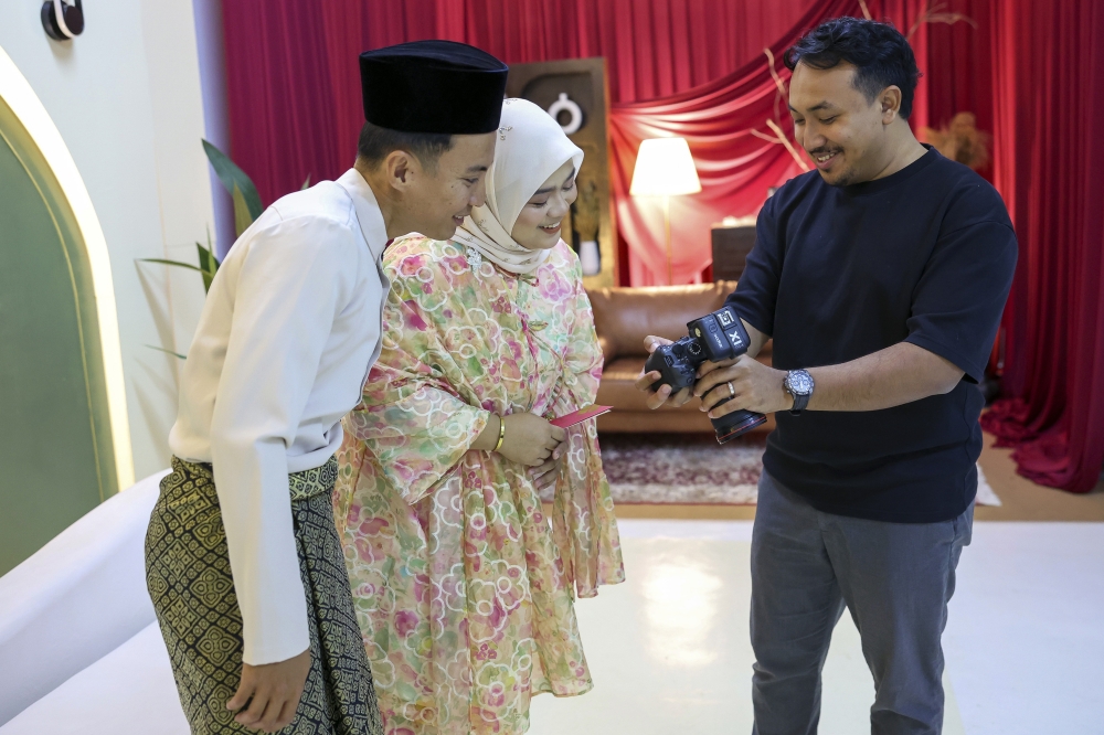 Photographer Muhammad Shahrul Eizwan Mohd Sukri interacts with his clients, Mohd Syafiq Fauzan Jaafar and Puteri Nursyafiqah Najwa Mohd Rizal, at his studio in Kuantan March 17, 2026. — Bernama pic