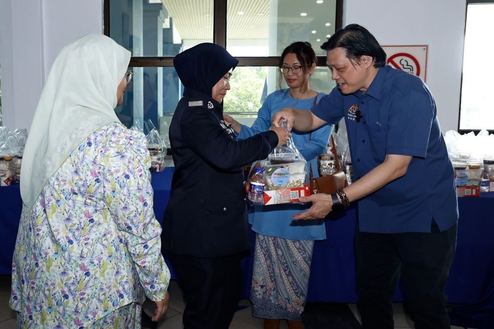 Political Secretary to the Prime Minister Chan Ming Kai (right) hands out ‘iftar’ packs to staff at the Melaka Contingent Police Headquarters on March 17, 2026 in recognition of their frontline service during Ramadan. — Bernama pic