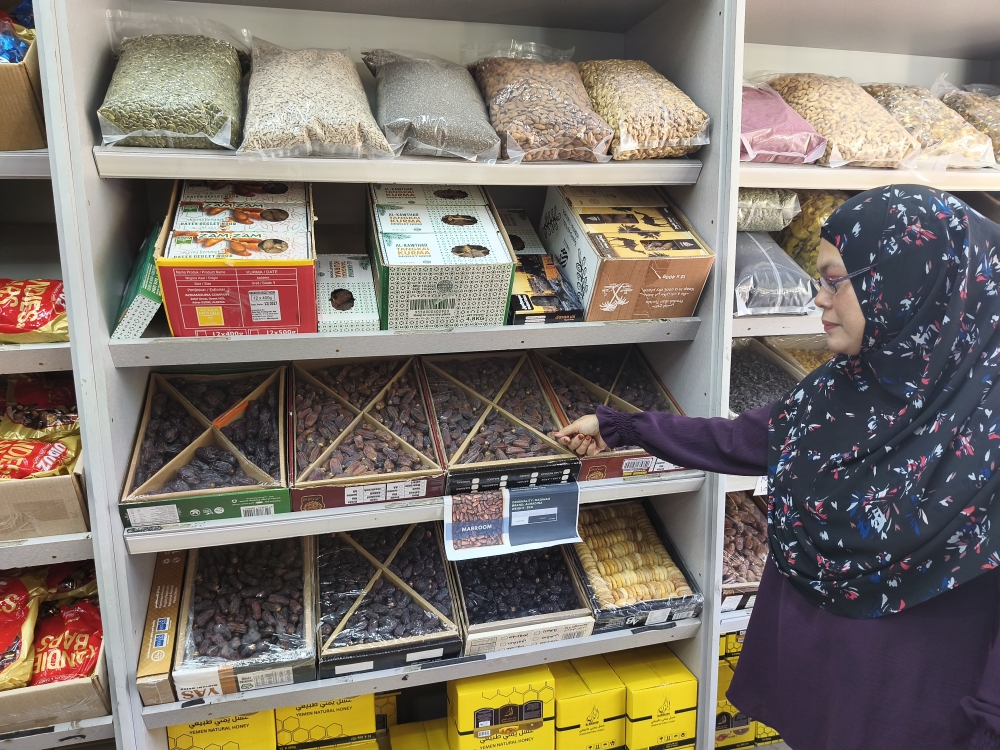Laili gesturing at a variety of imported dates from the Middle East being sold at Al Badr Trading in Danau Kota, Setapak. — Picture by Kenneth Tee