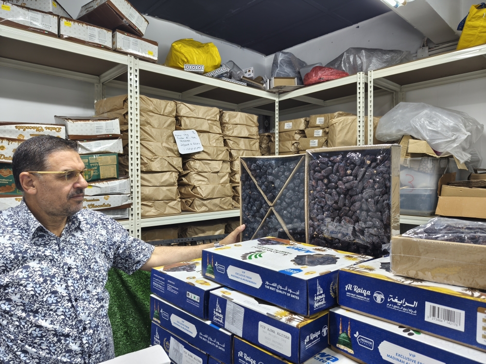 Salem posing with Ajwa and Safawi dates sourced from Medina, Saudi Arabia at his wholesale store in Danau Kota, Setapak. — Picture by Kenneth Tee