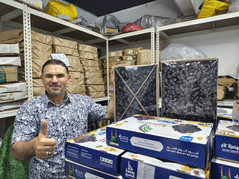 Salem posing with Ajwa and Safawi dates sourced from Medina, Saudi Arabia at his wholesale store in Danau Kota, Setapak. — Picture by Kenneth Tee