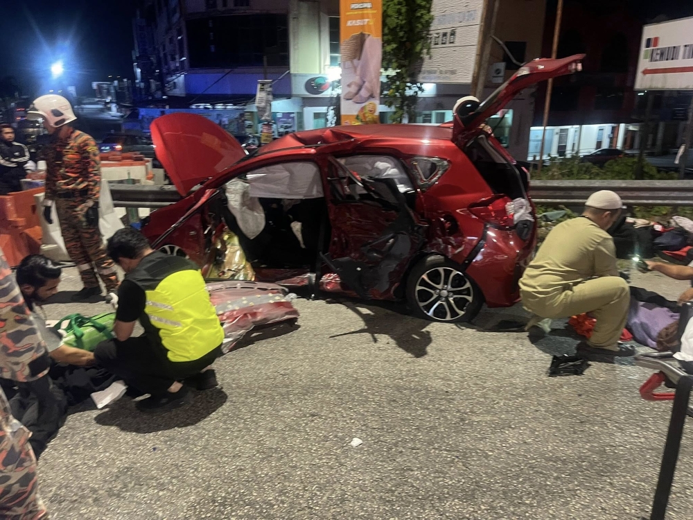 Rescuers are seen around a damaged Perodua Myvi that was involved in an accident with a BMW in Bandar Baru Tanah Merah on March 18, 2026. — Bomba pic