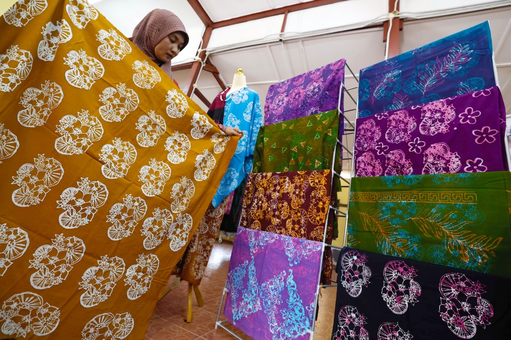 Workshop manager, Sapinah Sagap, 42, shows off some of the batik products with motifs of ox cart wheels and kesidang flowers during a tour of the Felda Hutan Percha Community Batik Terap Craft Product Development and Production Workshop, Alor Gajah March 18, 2026. — Bernama pic