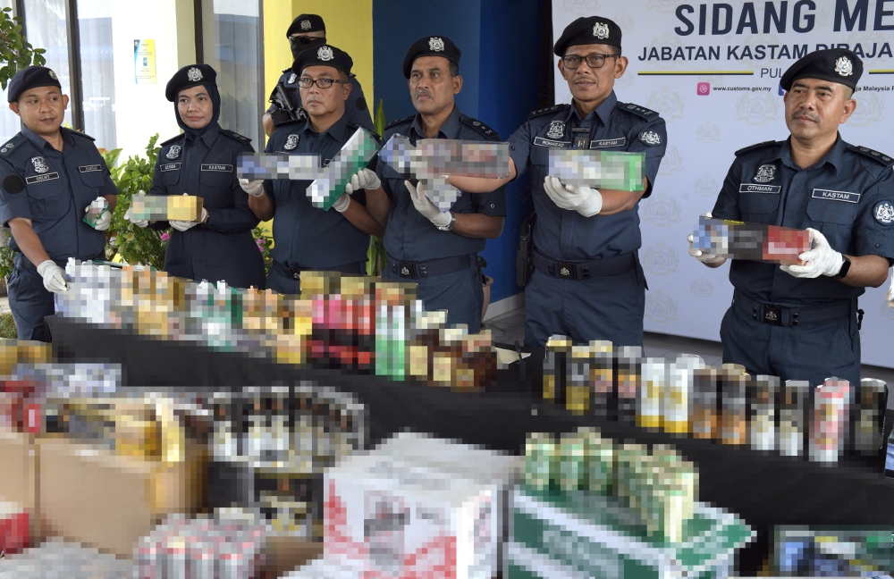 Penang Customs chief Datuk Rohaizad Ali (second right) and other officers hold up untaxed cigarettes and liquor worth RM3.9 million seized from three smuggling syndicates in separate raids around Bukit Mertajam during a press conference in Butterworth on March 18, 2026. — Bernama pic
