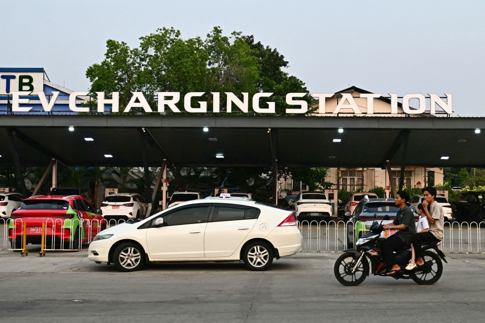 Electric cars at an EV charging station are seen in the background past other vehicles waiting to refuel at a petrol station in Naypyidaw on March 17, 2026. — AFP pic 