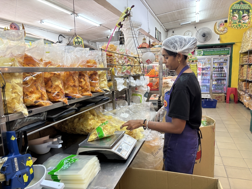 A worker packs kacang putih snacks at CTS Kacang Putih in Buntong, Ipoh, Perak. — Pictures by John Bunyan