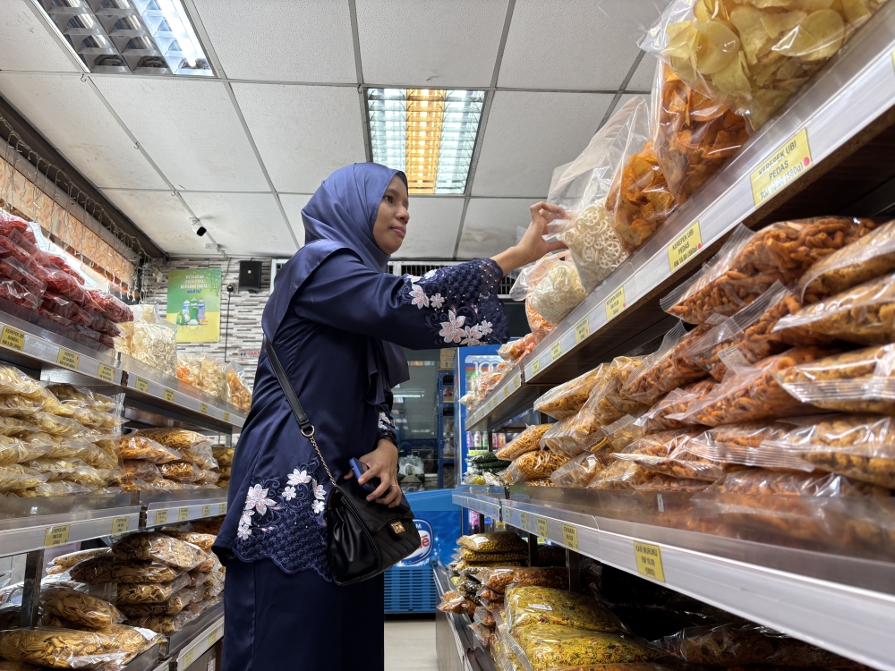 Norsyahira Zulkaple, 31, a nurse from Kuala Kangsar, buying kacang putih snacks for Hari Raya at Enak & Rangup Kacang Putih kacang shop located at Buntong in Ipoh, Perak.— Pictures by John Bunyan