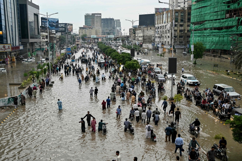 People wade through a flooded street after heavy rainfall in Karachi on August 19, 2025. — Reuters file pic