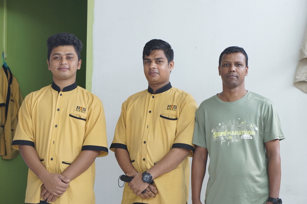 Mohd Julhash (right) and Zainal Abidin (centre), who've spent their Hari Raya mornings with friends before heading to work, with a colleague at their workplace in Kuala Lumpur. — Picture by Arif Zikri