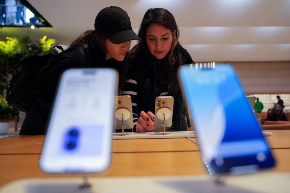 People look at iPhones on display at the Apple Fifth Avenue store in New York City, US on May 23, 2025. — Reuters pic