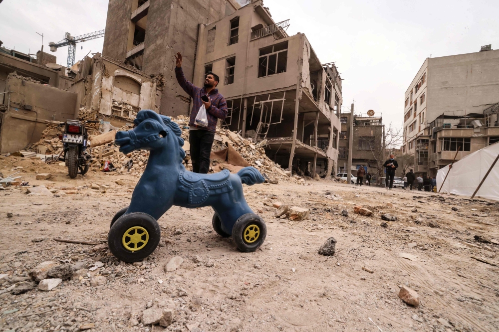 An Iranian man  gestures as he stands near destroyed homes following a military strike on the Iranian capital Tehran on March 15, 2026. — AFP pic