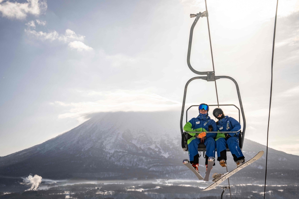 This picture taken on February 20, 2026 shows foreign tourists riding on a ski lift at the Niseko Tokyu Grand Hirafu ski resort as Mount Yotei looms in the background, in Kutchan, Hokkaido prefecture. — AFP pic 