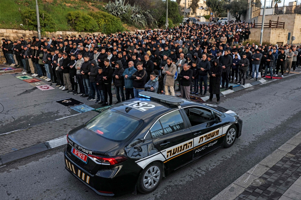 An Israeli police vehicle moves past Muslim worshippers gathering outside the Jerusalem old city walls on March 20, 2026 to attend attend the early morning prayers for Eid al-Fitr, marking the end of the holy month of Ramadan. — AFP pic