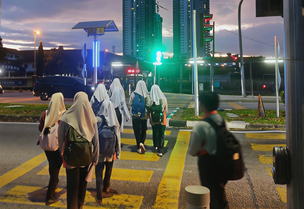 Students make their way across the road outside SMK Puchong Permai early in the morning. — Picture by Muhammad Yusry