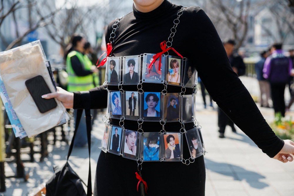 A fan of Kpop group BTS, wearing photographs of the band’s members, heads to the venue of the ‘BTS The Comeback Live Arirang’ concert, in central Seoul, South Korea, March 21, 2026. — Reuters pic