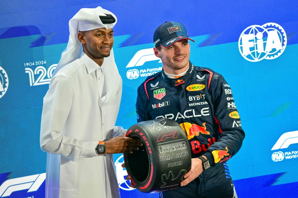 Red Bull’s Max Verstappen receives the pole position trophy from Qatari athlete Mutaz Essa Barshim after qualifying for the Formula One Grand Prix at Lusail International Circuit in Doha, November 30, 2024. — AFP pic