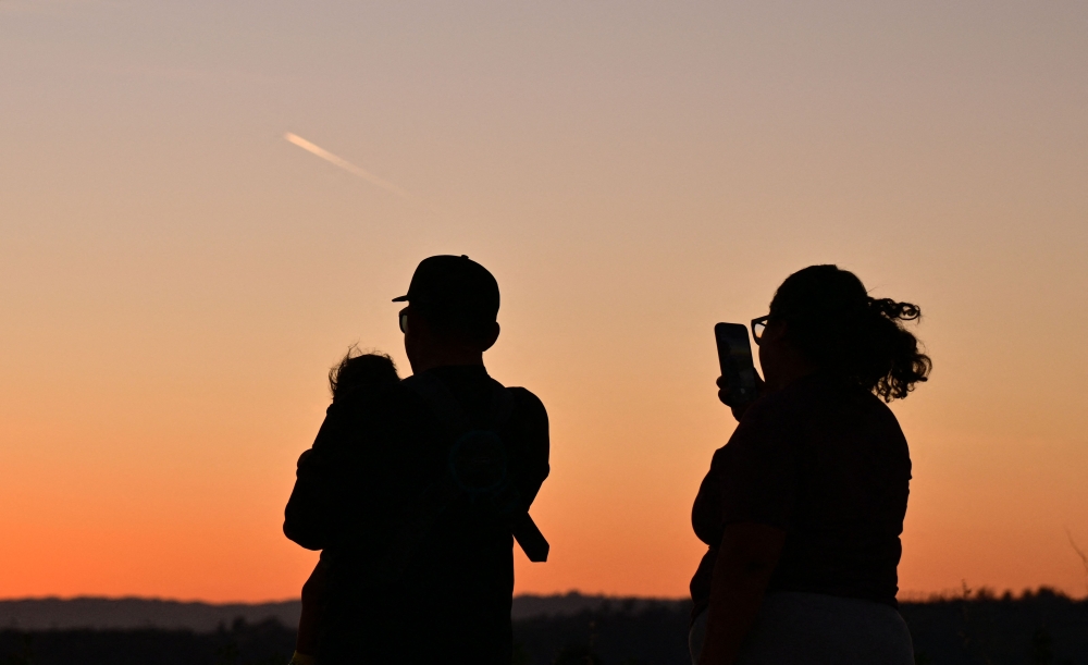 A family watches the last moments of twilight as the sun sets in Los Angeles, California, on March 18, 2026. A rare March heatwave is hitting California and the National Weather Service is warning against strenuous activity during the hottest times of the day. — AFP pic