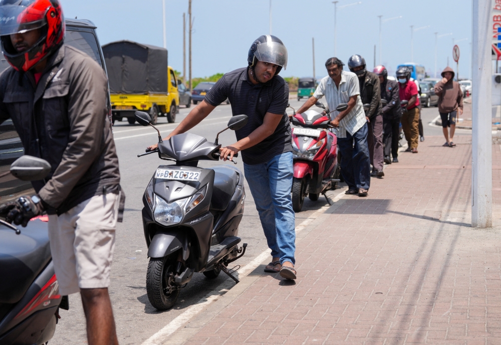 People in a queue push their scooters as they wait to refuel, outside a fuel station, after the government declared a weekly Wednesday holiday for public officials to conserve fuel, amid concerns over fuel supplies during the US-Israeli conflict with Iran, in Colombo March 18, 2026. — Reuters pic