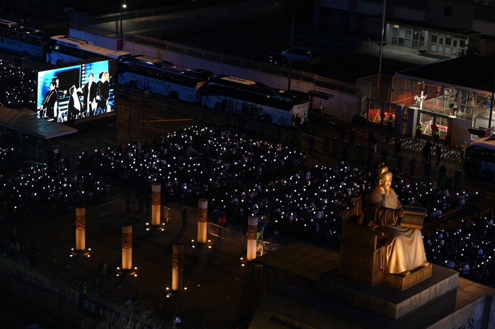 Fans watch the concert of K-pop boy group BTS on a screen in Seoul on March 21, 2026. — Pool/AFP pic