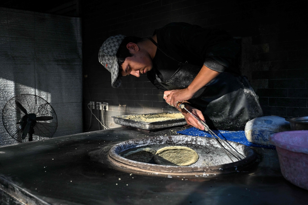 A Chinese ethnic Uyghur Muslim man bakes ‘naan’ ahead of Eid al-Fitr, which marks the end of the Muslim fasting month of Ramadan in Beijing on March 19, 2026. — AFP pic