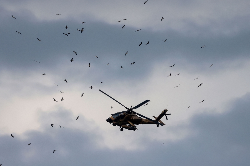 An Israeli helicopter gunship flying along the Lebanon-Israel border in the Upper Galilee crosses the path of migrating white storks (Ciconia ciconia) making their way from Africa to Europe, over northern Israel on March 22, 2026. — AFP pic