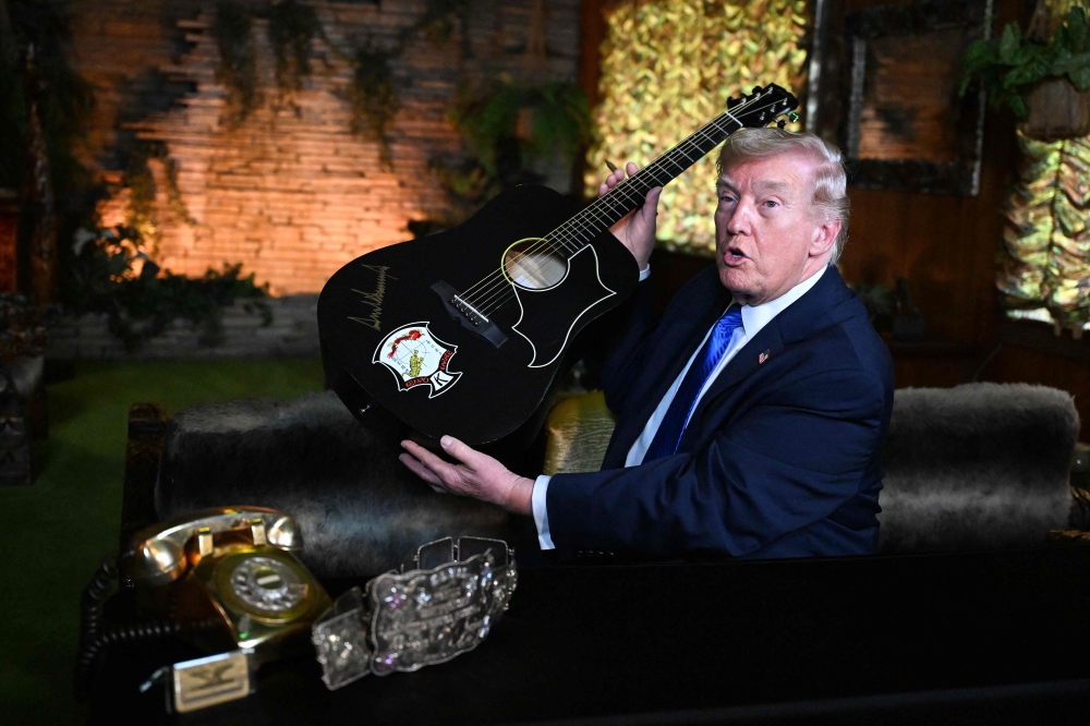 US President Donald Trump holds a replica of one of Elvis Presley’s guitars after he signed it, as he tours the Jungle Room during his visit to Graceland in Memphis, Tennessee, March 23, 2026. — AFP pic
