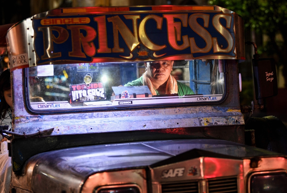 Jeepney driver Eric Helera sits in the driver’s seat while waiting for passengers before starting his route from a terminal in Manila March 23, 2026. — AFP pic