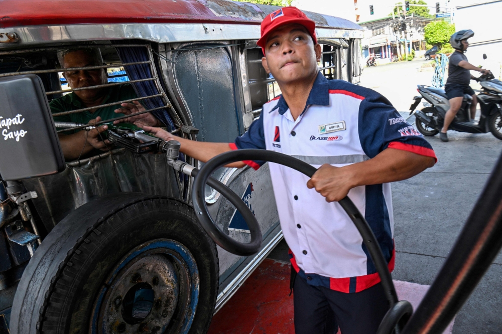 Jeepney driver Eric Helera refuels his vehicle with diesel at a fuel station in Manila March 23, 2026. — AFP pic