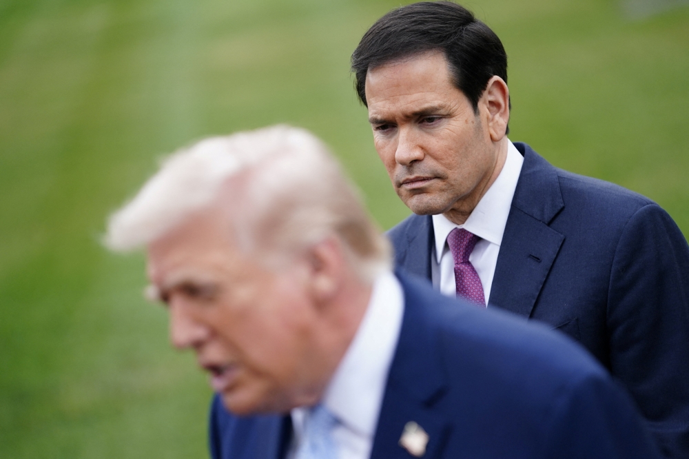 US Secretary of State Marco Rubio listens to US President Donald Trump speaking to the media, as Trump departs the White House for Florida, in Washington March 20, 2026. — Reuters pic